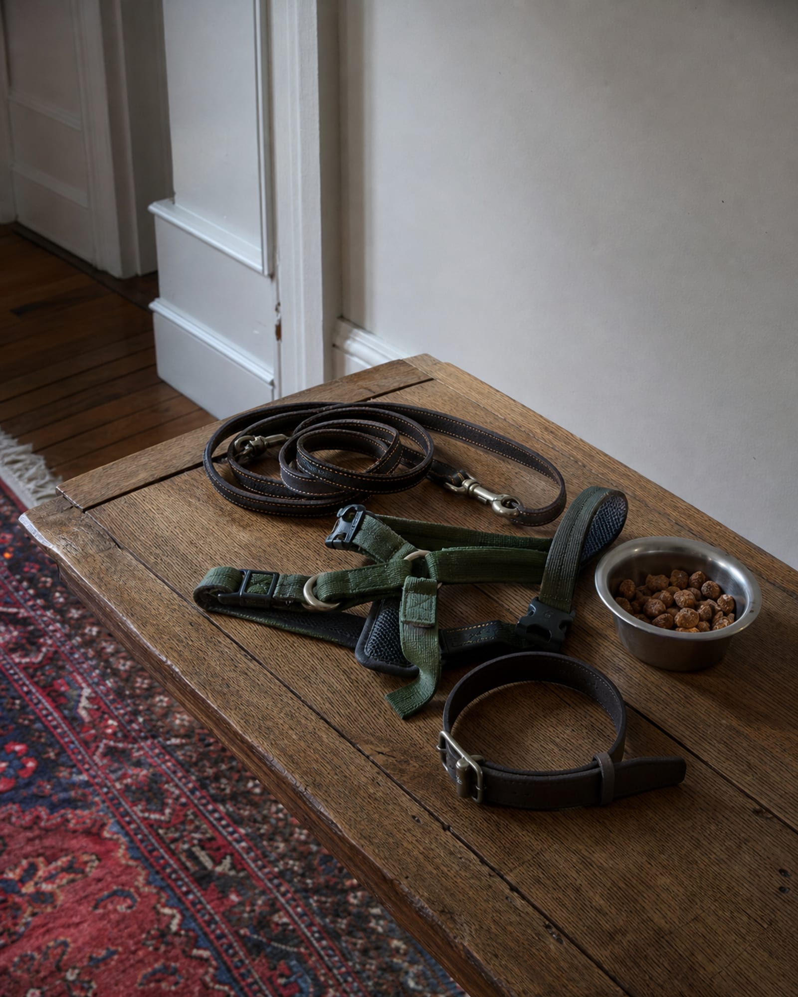 A still life of a flat collar, a harness and training treats on a wooden surface, no dog