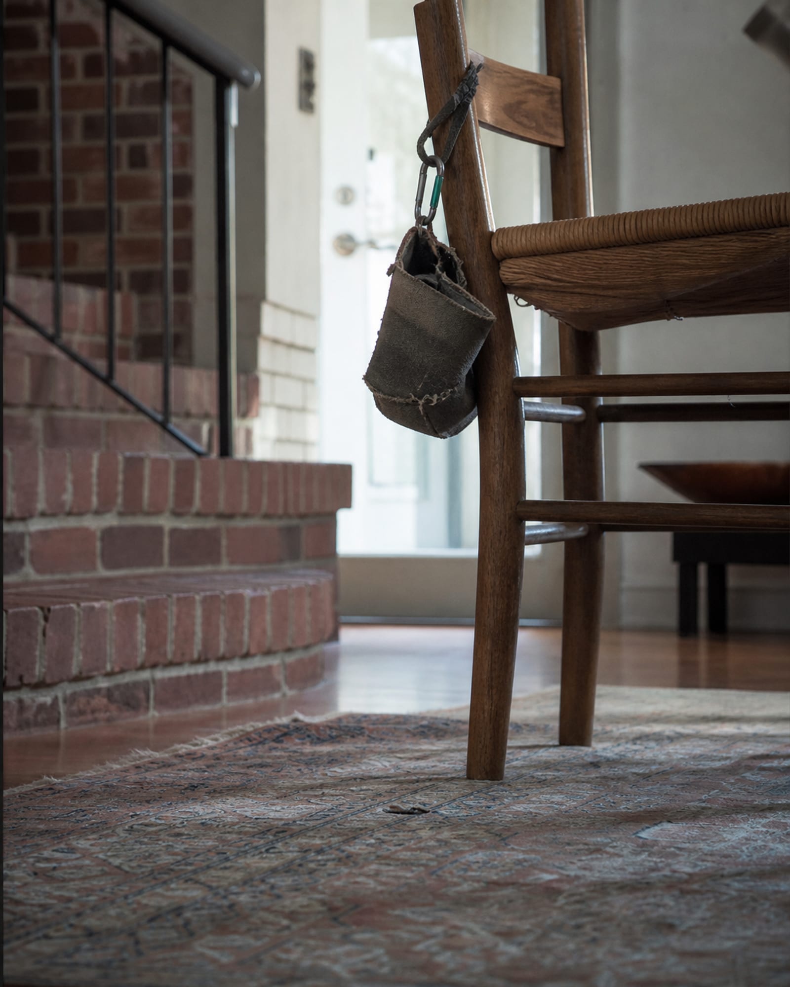 A treat pouch worn at the seams hanging on a chair back, no dog